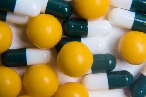 White-green pill capsules and orange round vitamins close-up, medical concept Stock Photos