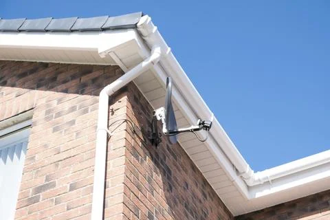 White gutter runs along brick roofline Stock Photos