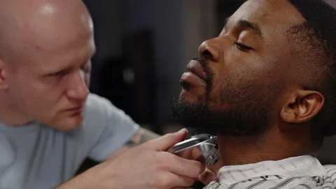 White guy shaving his beard with a trimmer to an African American guy - close-up Stock Footage 170576210