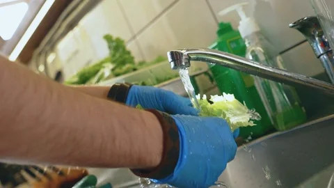 White guy washes leaves of lettuce for burger under running water. slowmotion Stock Footage 104649666