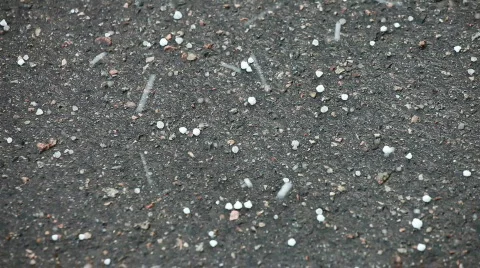 White hailstones bouncing off black asphalt Stock Footage