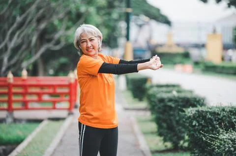 White-haired elderly person exercising in the park early in the morning. Stock Photos