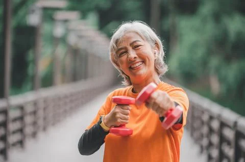 White-haired elderly person exercising in the park early in the morning. Stock Photos