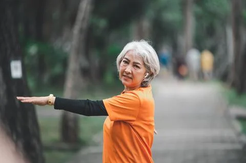 White-haired elderly person exercising in the park early in the morning. Stock Photos