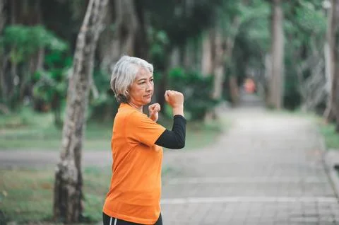 White-haired elderly person exercising in the park early in the morning. Stock Photos