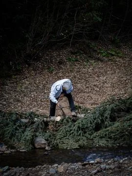 The white-haired man cuts down the fallen tree to clear the way. Stock Photos