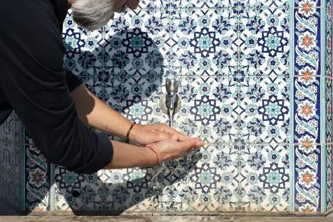 A white-haired man does hand washing on a sunny day in the east Foto stock