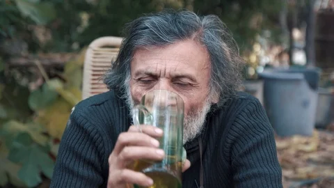 The white-haired man drinking beer and intently look at the camera Stock Footage 85670604