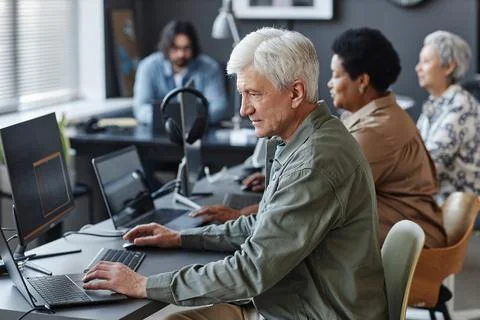 White haired man using computer in programming class for seniors Stock Photos