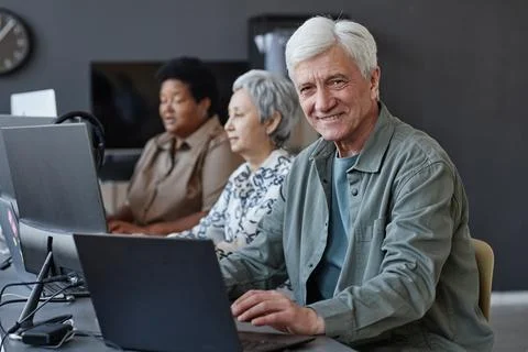 White haired senior man in computer class for elderly smiling at camera Stockfoto's