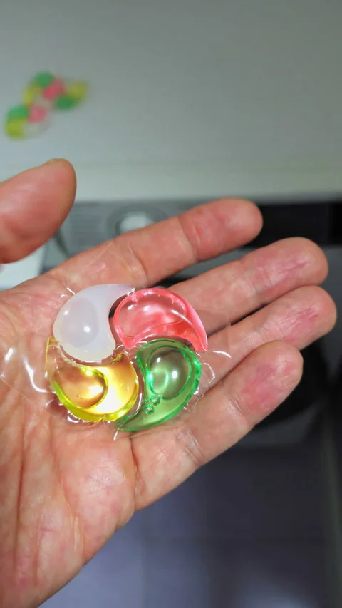 White hand holding washing machine detergent capsules Stock Footage 273943607