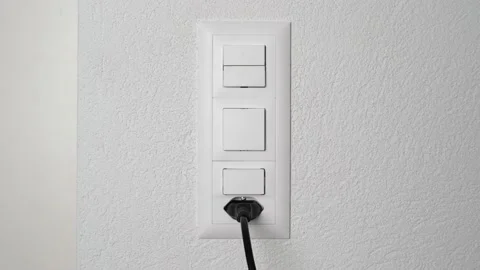 White hand pulls aggressively on a black cable to unplug it from power outlet. Stock Footage 147849479