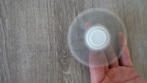 White hand spinner, or fidgeting spinner, rotating on man's hand Stock Footage 76376033