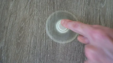 White hand spinner, or fidgeting spinner, rotating on the floor Stock Footage 76376384