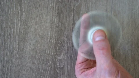 White hand spinner, or fidgeting spinner, rotating on man's hand Stock Footage 76376649