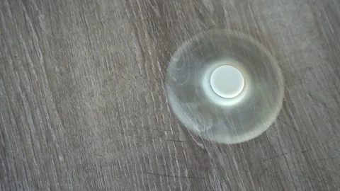 White hand spinner, or fidgeting spinner, rotating on the floor Stock Footage 76376946