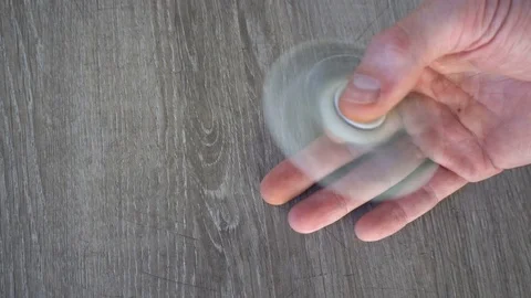 White hand spinner, or fidgeting spinner, rotating on man's hand Stock Footage 76377161