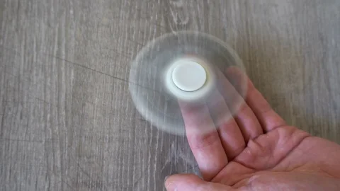 White hand spinner, or fidgeting spinner, rotating on man's hand Stock Footage 76377300