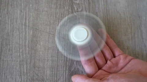 White hand spinner, or fidgeting spinner, rotating on man's hand Video stock 76423402