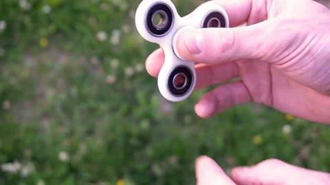 White hand spinner, or fidgeting spinner, rotating on child's hand Stock Footage 76971917