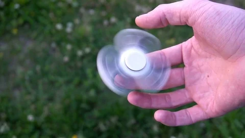 White hand spinner, or fidgeting spinner, rotating on child's hand 스톡 동영상 76972038