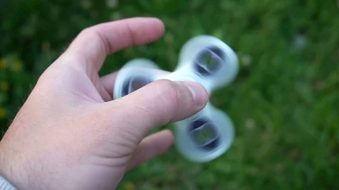 White hand spinner, or fidgeting spinner, rotating on child's hand Stock Footage 76972222