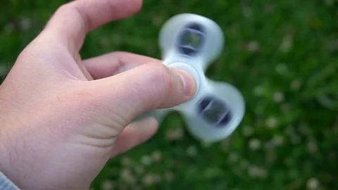 White hand spinner, or fidgeting spinner, rotating on child's hand Stock Footage 76972314