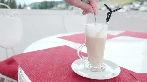 White hand with a teaspoon stirring delicious latte in a large coffee cup Stock Footage 147553996