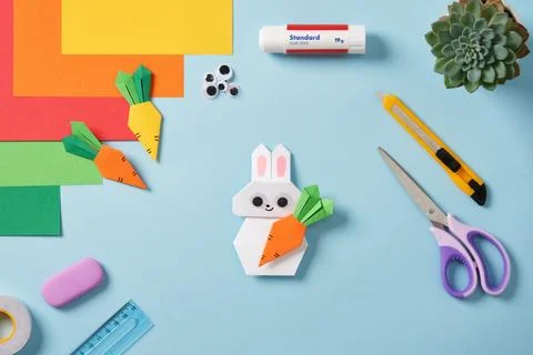 White handmade origami paper rabbit holding a carrot, as well as other pape.. Stock Photos