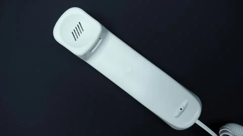 White handset with cable of old push-button telephone shines in darkness Stock Footage 287932355