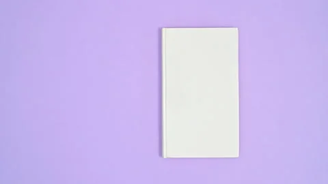 White hardcover opened book appear on purple theme, close and open. Stop motion Stock Footage 165448084