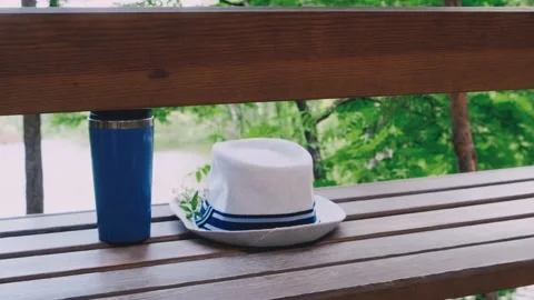 White hat and thermo cup on the wooden swing outdoor. Stock Footage 197541253
