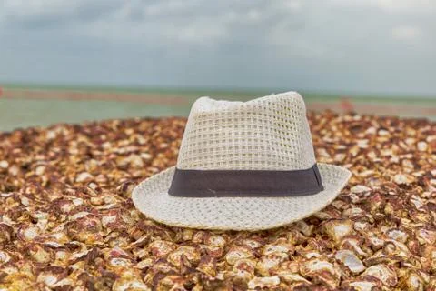 White hat lies on a shell stone beach on a blurred background of blue sea Stock Photos