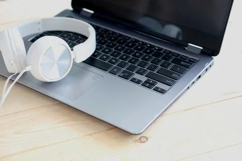 White headphone and laptop computer on wooden background Stock Photos