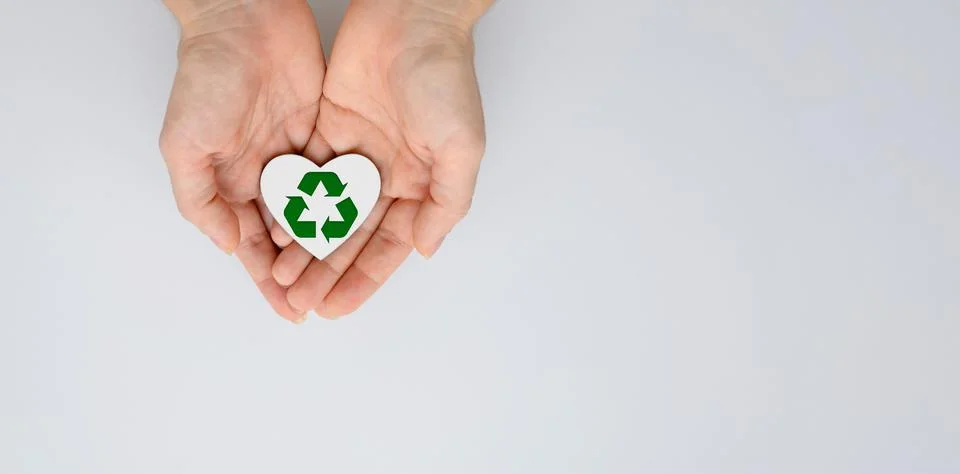 White heart with a recycling sign in female hands. copyspace. Stock Photos