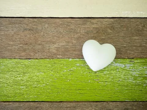 White heart shape stone on rustic wooden planks with green painted texture... Stock Photos