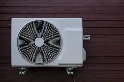A white heat pump unit mounted on a red wood panel Stock Photos
