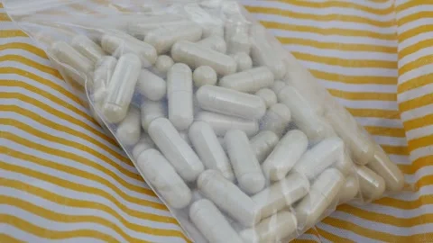 White herbal supplement capsules in clear ziplock Видео 330764176