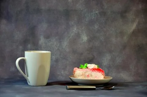 White high ceramic mug with black coffee, next to a plate with a piece of bis Stock Photos