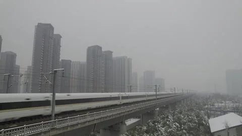 White High Speed Train Blurs Past Snowy Elevated Tracks in Foggy Urban Cityscape Video stock 336545862