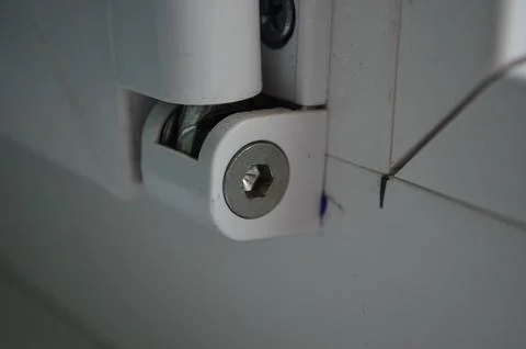A white hinge with a silver screw on it. Stock Photos