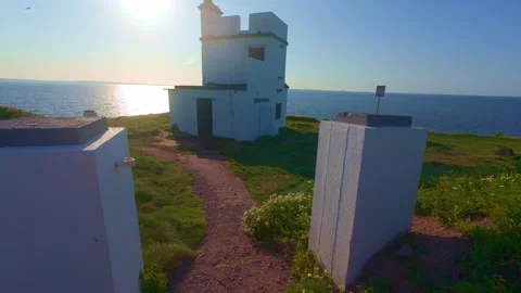White historic lighthouse compound standing on scenic coastal cliff in ireland Stock Footage 340432580