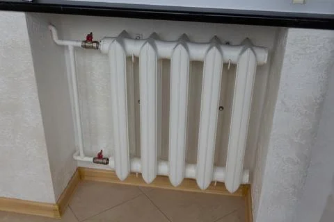 White home heating battery section mounted under a window sill on a texture.. Stock Photos