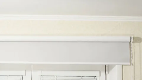 White horizontal blinds and rolled curtain at a window with a frame from white Stock Footage 79650774