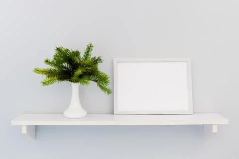 A white horizontal frame stands on a shelf with fir branches Stock Photos