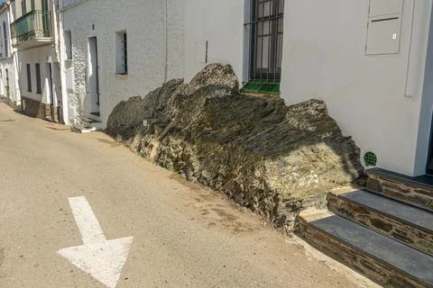 The white house is built on a stone that forms part of the sidewalk. Stock Photos