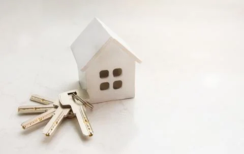 A white house model with a bunch of keys lie on a white floor. Copyspace Stock Photos