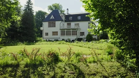 The white house is surrounded by dense vegetation on a hill. Video stock 165520836