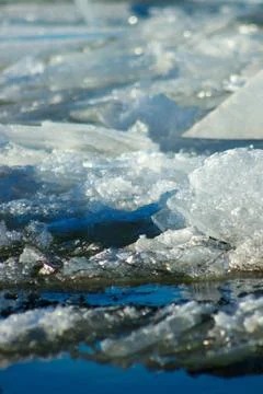 White ice floating on background of blue water. Stock Photos