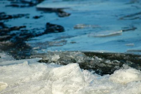 White ice floating on background of blue water. Stock Photos